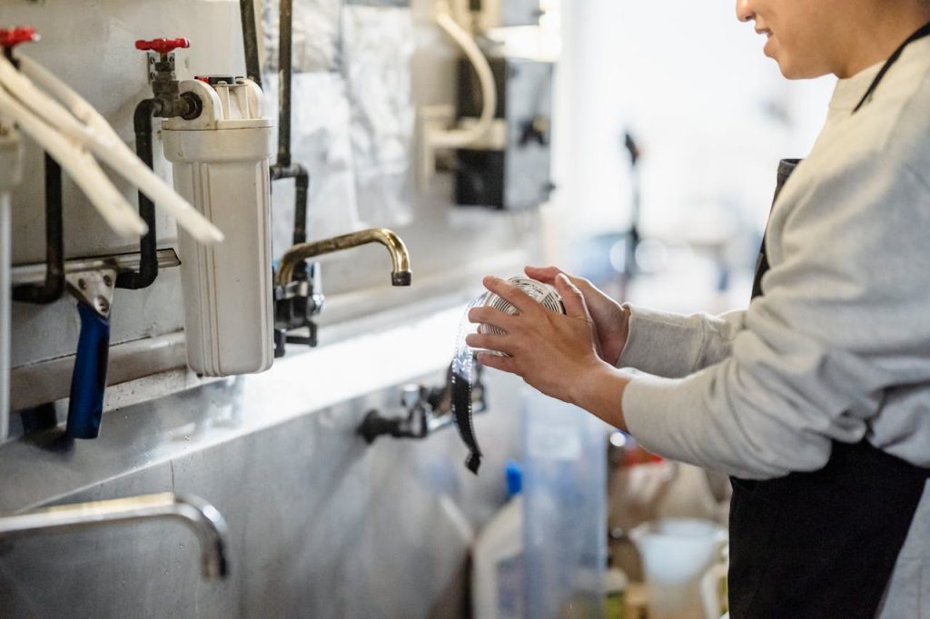 A person processes film in a darkroom with visible plumbing and equipment, showcasing the art of traditional photography.